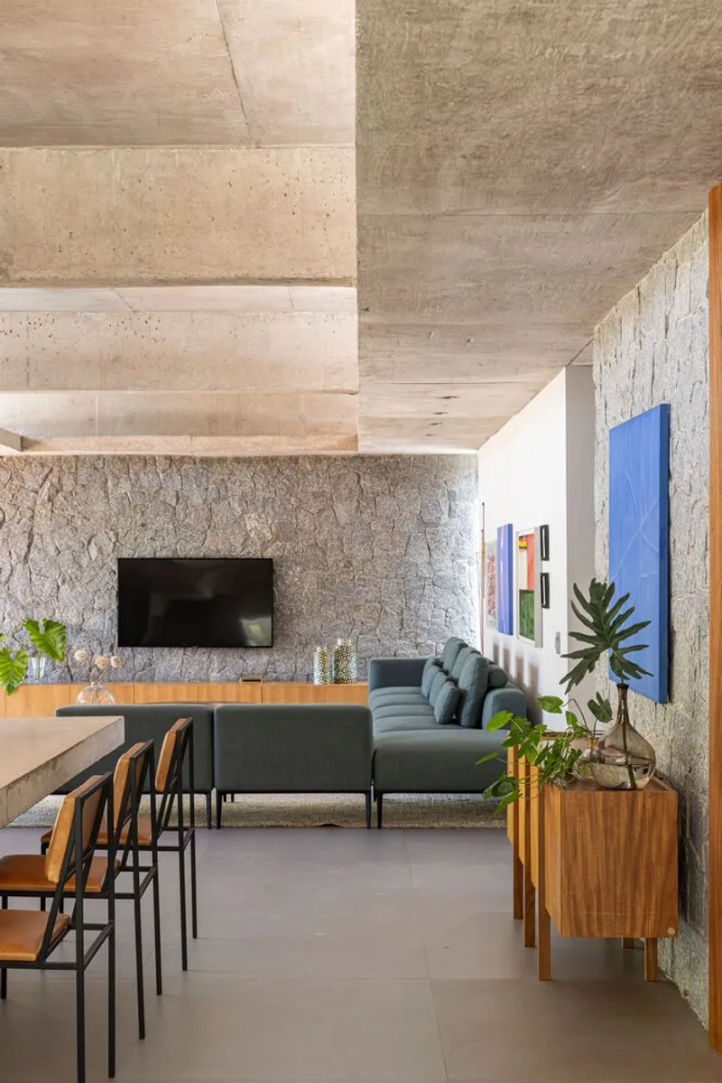 Open living space with board-formed concrete ceiling and stone wall beneath linear skylights