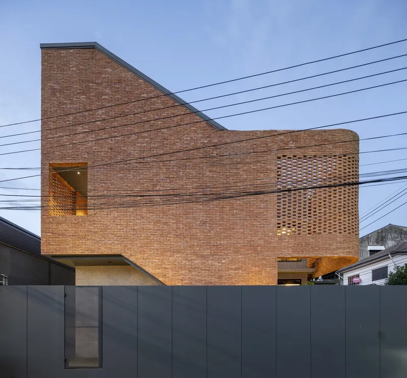 Street view of the cantilevered brick facade with perforated screen sections and power lines crossing the sky