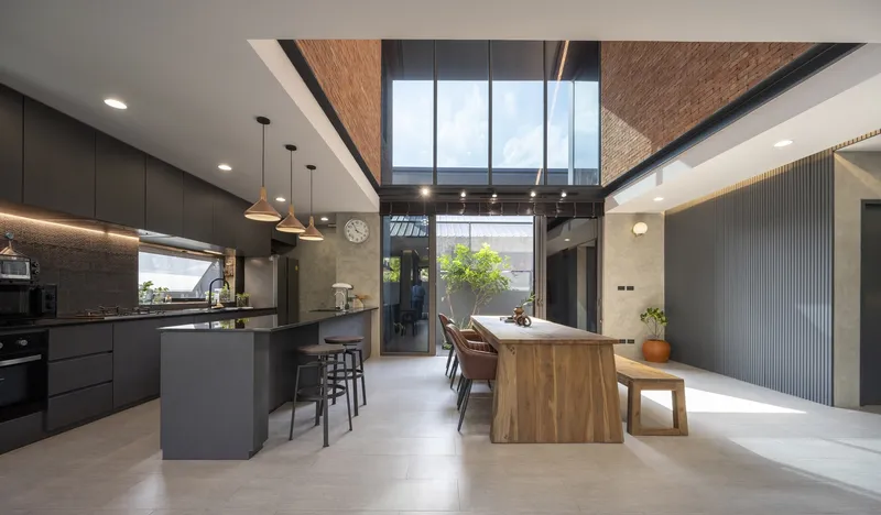 Open-plan kitchen and dining space under a clerestory skylight with exposed brick soffit