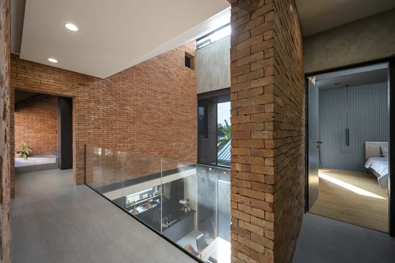 Upper level hallway with exposed brick walls and a glass floor opening overlooking the living space below