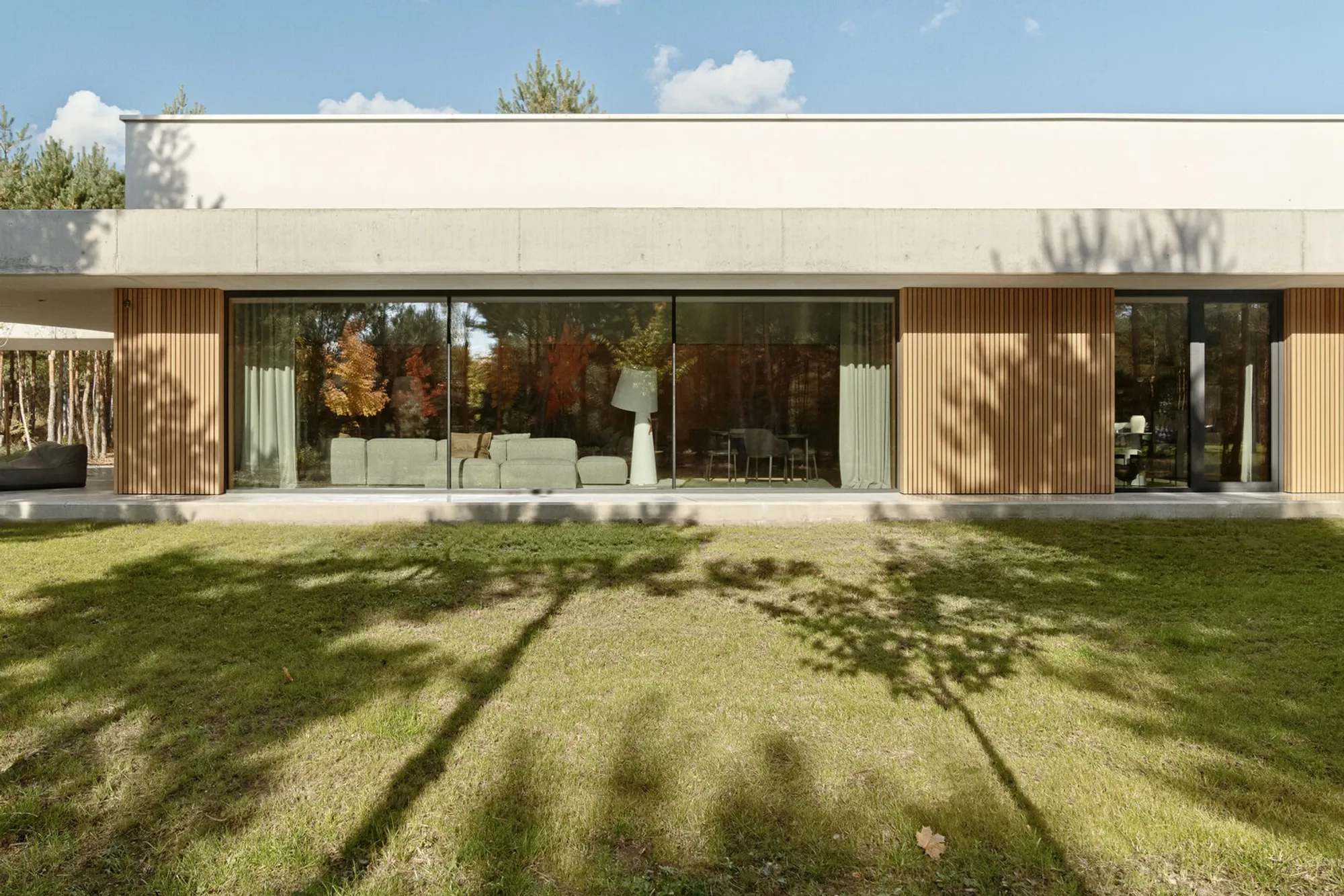 PL.Architekci Frames a Poznań Family Home in Concrete and Timber Against a Pine Forest