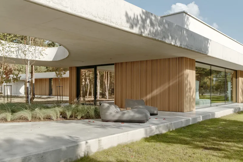 Covered terrace with vertical timber cladding and concrete platform beneath a hovering white roof on a clear day