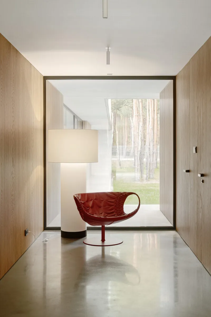 Corridor with timber-clad walls and polished concrete floor framing a view of the forest