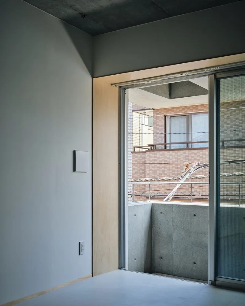 Sliding glass door opening onto concrete balcony with view of neighboring brick building and drying rack