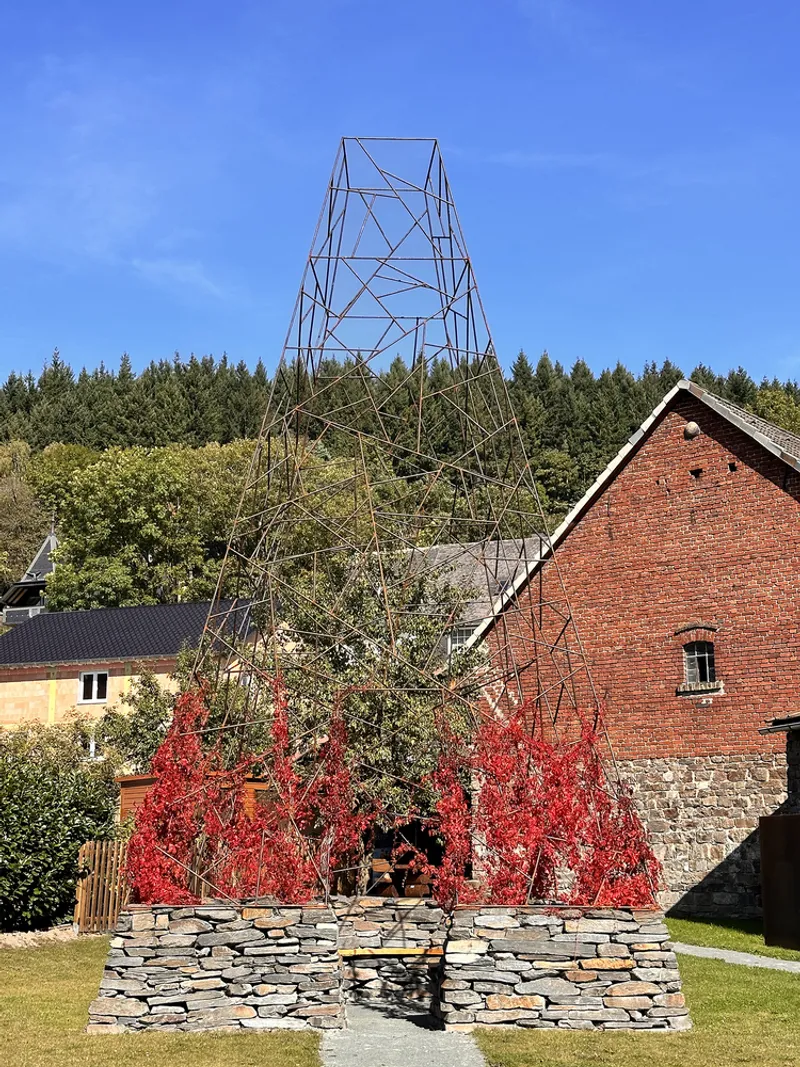 Circular slate stone bench surrounding a bare tree with autumn foliage and brick barn beyond