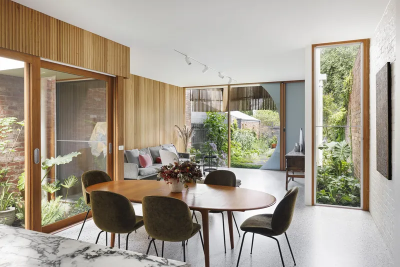 Open-plan dining and living space with circular window and glazed courtyard openings