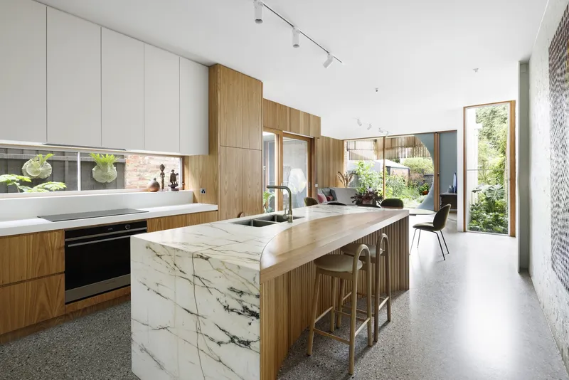 Kitchen with marble-clad island and timber cabinetry opening to living areas beyond