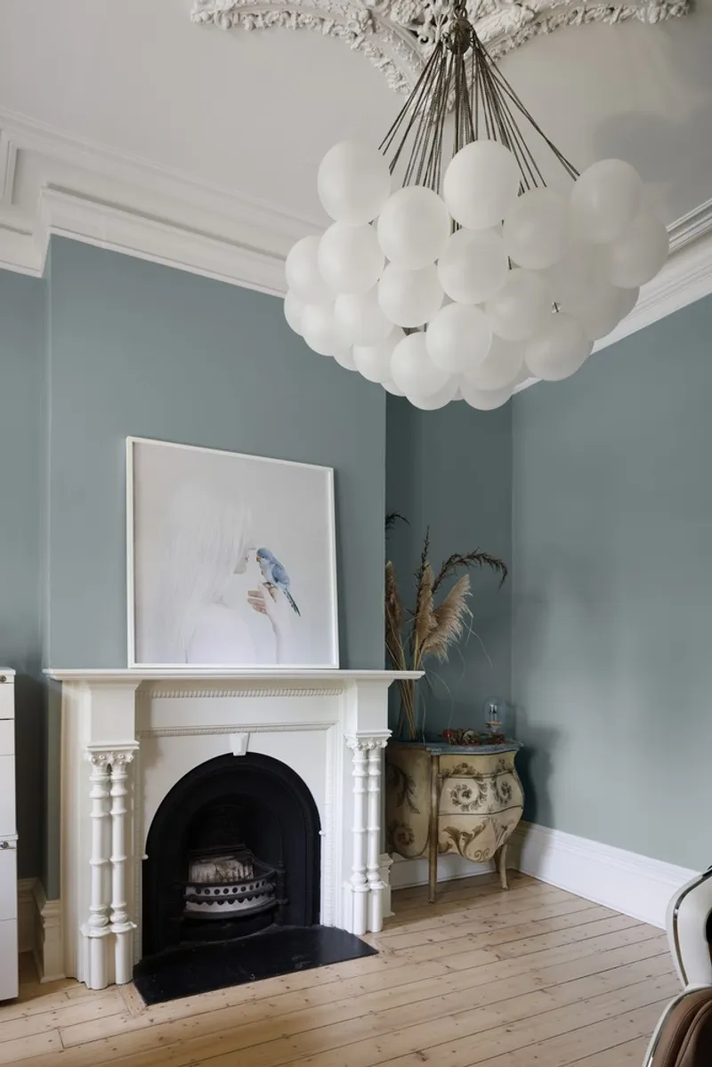 White marble fireplace with globe chandelier suspended from ornate ceiling medallion