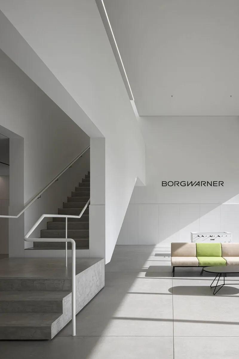 Interior lobby showing the staircase, polished floor, and seating area under angular ceiling planes