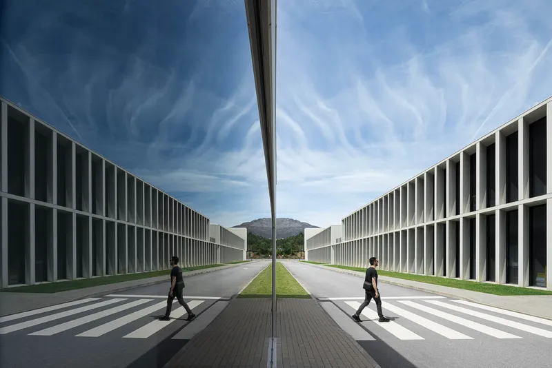 Symmetrical courtyard framed by flanking buildings with vertical fins and two people crossing at zebra crossings