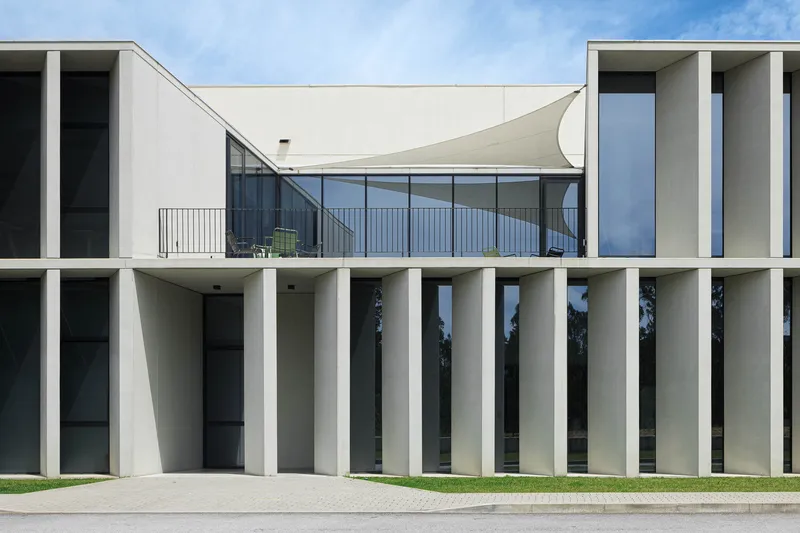 Facade detail showing the curved tensile canopy over glazing and vertical concrete columns below