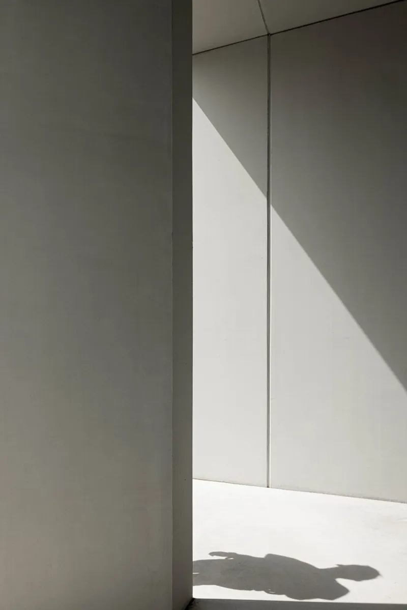 Corner detail of white plaster walls with sharp shadow cast by afternoon sunlight