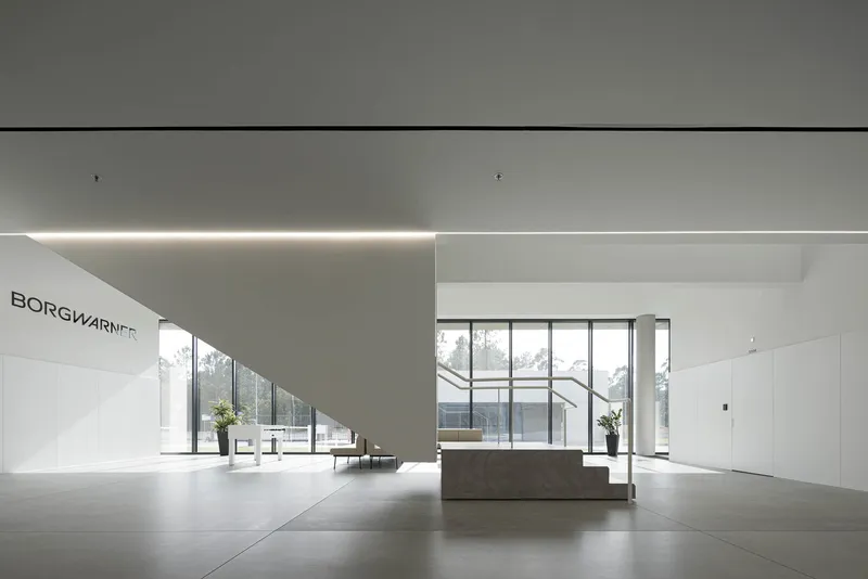Reception lobby with central stone desk and floor-to-ceiling windows overlooking trees