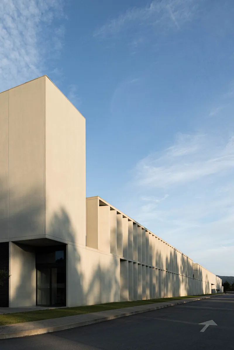 Corner tower and louvered facade catching late afternoon sunlight on the pavement