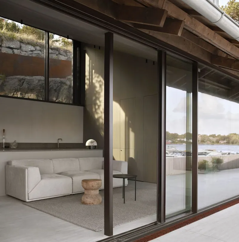 Sliding glass doors opening from the living area to a terrace with dappled afternoon sunlight