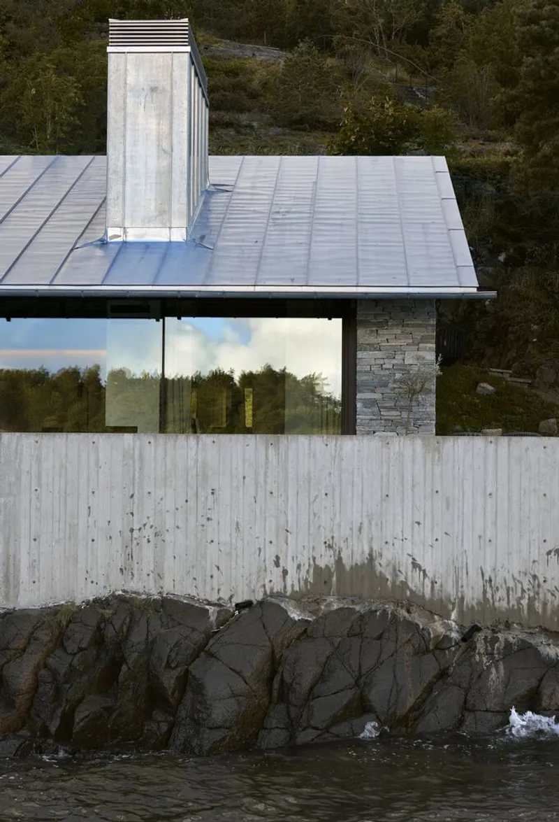 Waterfront view showing the concrete retaining wall, metal roof chimney and rocky shoreline