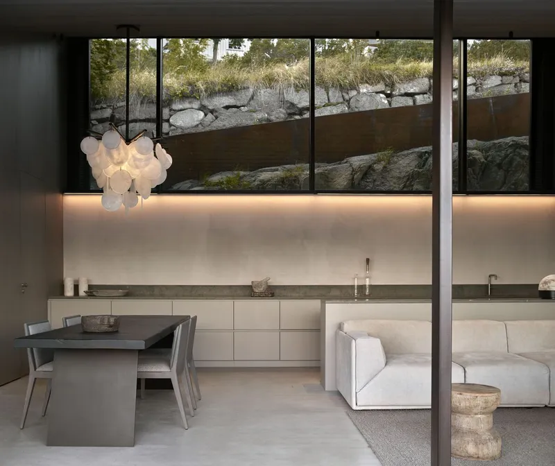 Open-plan kitchen and living area with backlit cabinetry overlooking the rocky water's edge