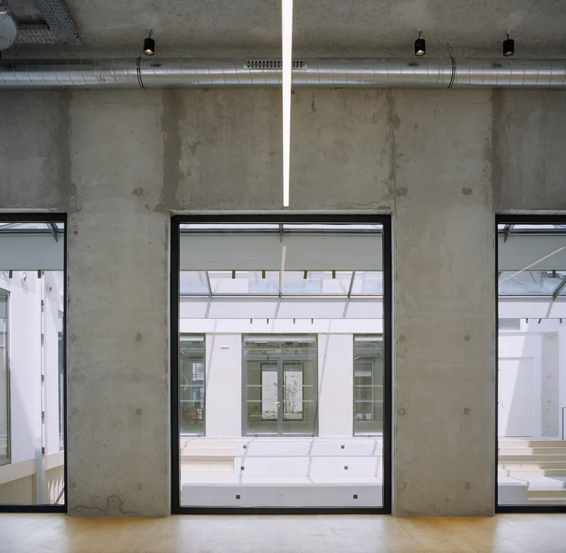 Interior window framing a view through the courtyard to the opposite building facade under diffused daylight
