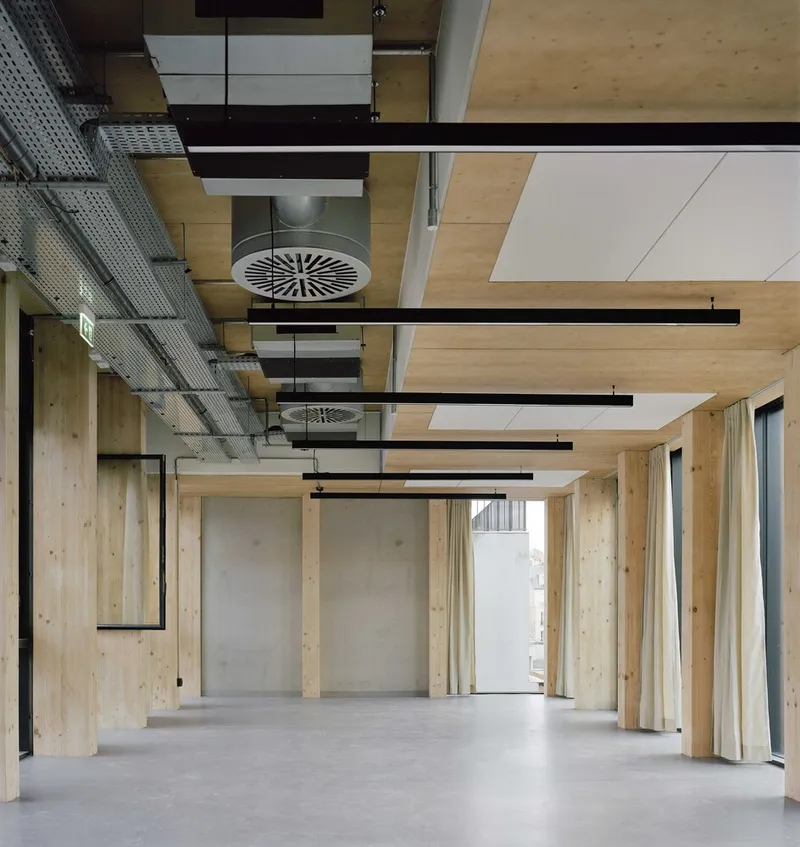 Ceiling detail showing timber panels, exposed black beams, round ventilation diffuser and pendant fixtures