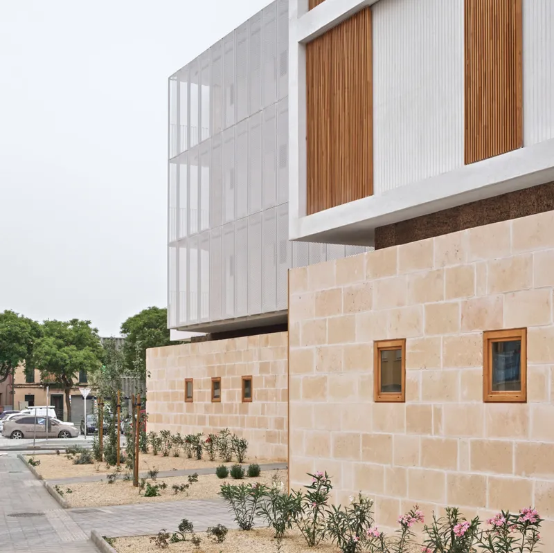 Stone base with timber windows supporting cantilevered volume with perforated screens and planted sidewalk