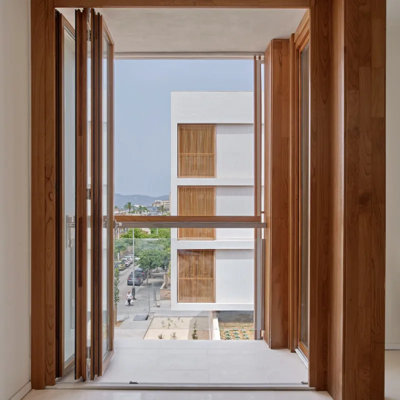 Timber folding doors opening from an interior room to a view of the opposite facade block