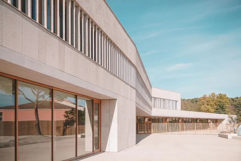 Curved precast concrete facade with vertical brise-soleil above timber-framed glazing and exterior terrace