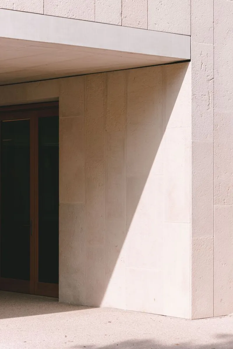 Exterior entrance with angled plywood soffit meeting textured concrete block walls in bright daylight