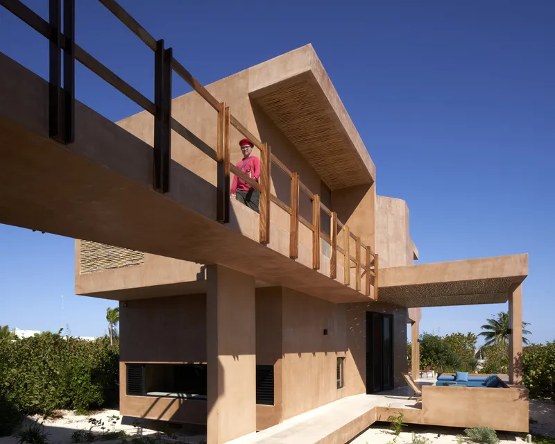 Cantilevered terrace with timber railing and woven ceiling soffit occupied by a person in pink
