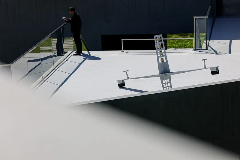 White roof terrace with diagonal metal handrail and rooftop mechanical equipment casting sharp afternoon shadows