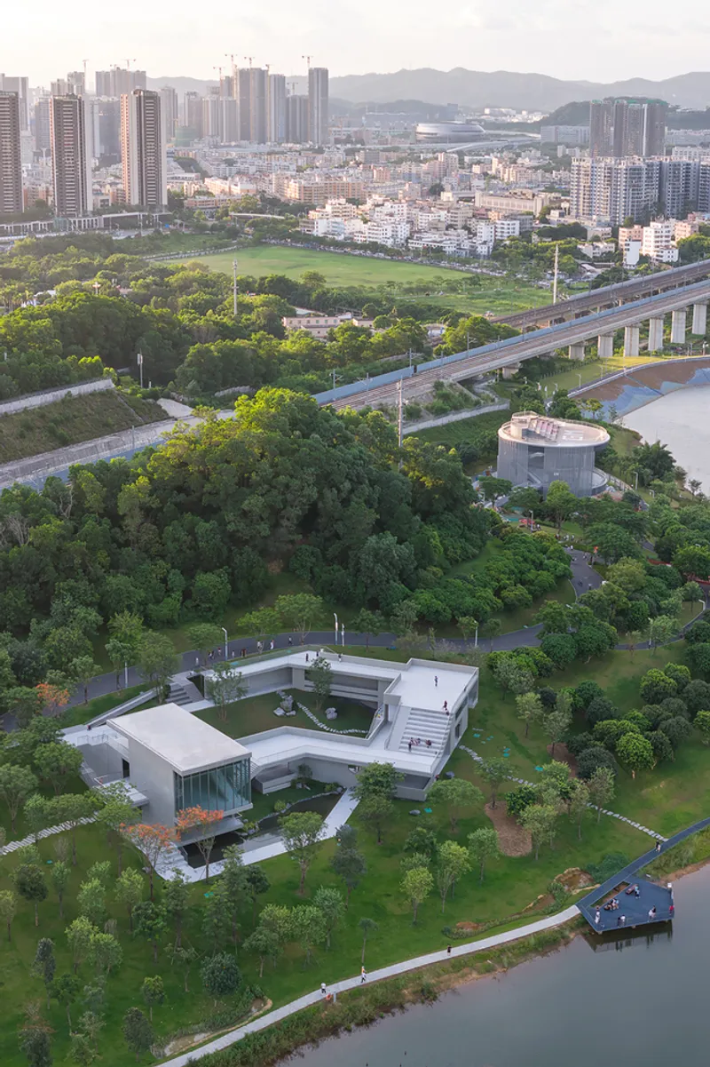 Drone view showing the complex beside a waterway with elevated highway and dense urban towers beyond