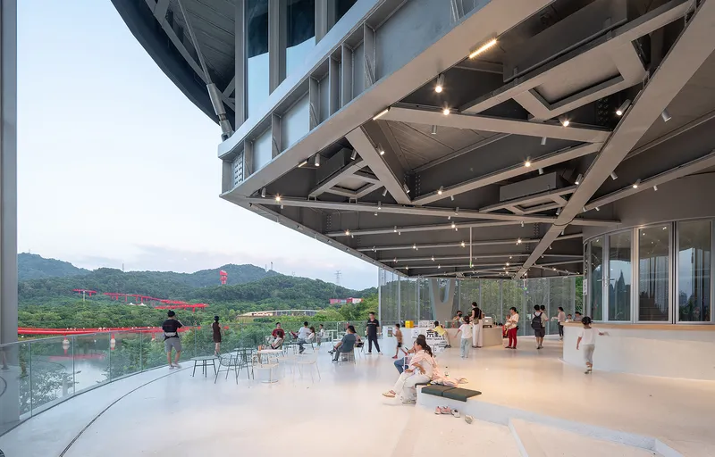 Cantilevered terrace with exposed diagonal steel trusses and glass balustrade overlooking the lake