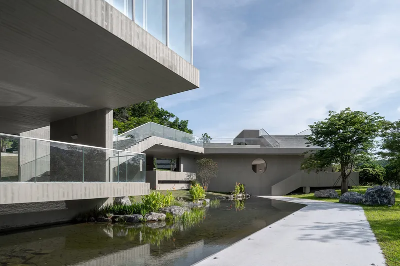 Cantilevered concrete terrace above a reflecting pool with planted edges and natural stone outcrops
