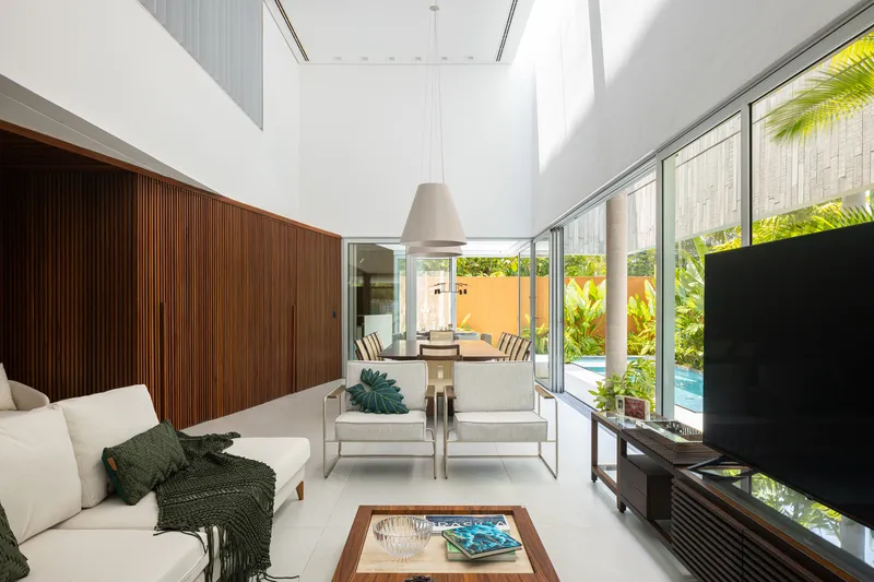 Living room with slatted timber wall and full-height glazing opening to the planted courtyard pool