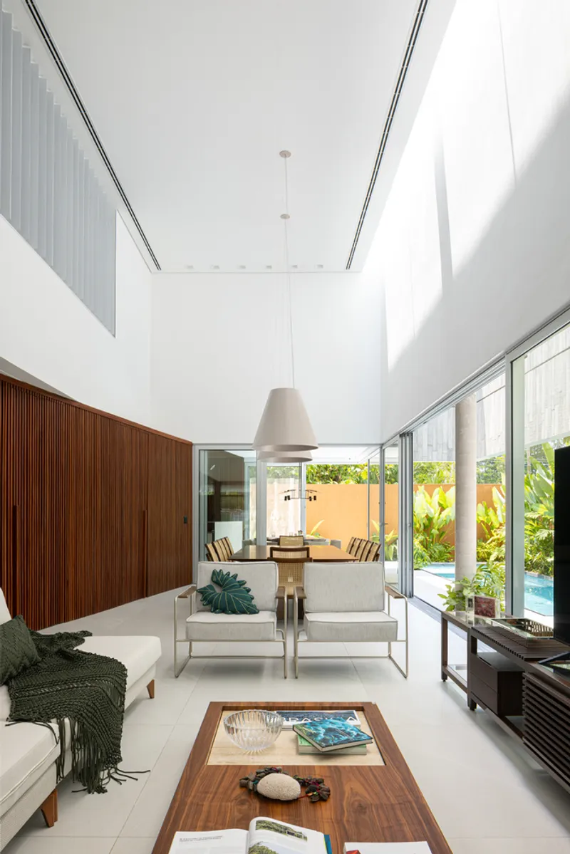 Double-height living room with timber wall panel and pendant light overlooking the pool courtyard