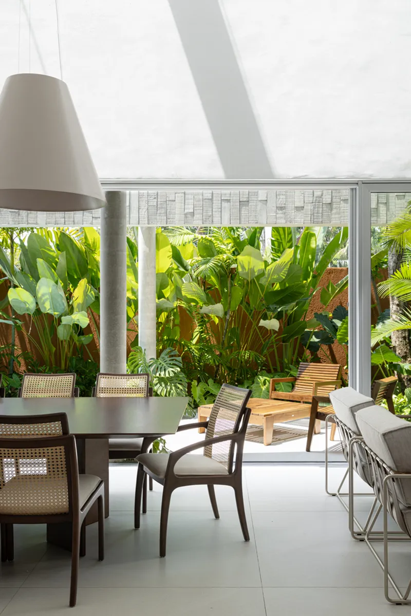 Dining area beneath a sloped skylight with views to a planted garden wall of palms and traveler's palms