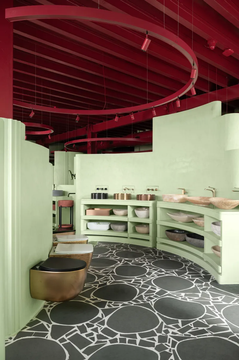 Curved vanity counter with open shelving displaying ceramic bowls and vessels below red metal ceiling structure