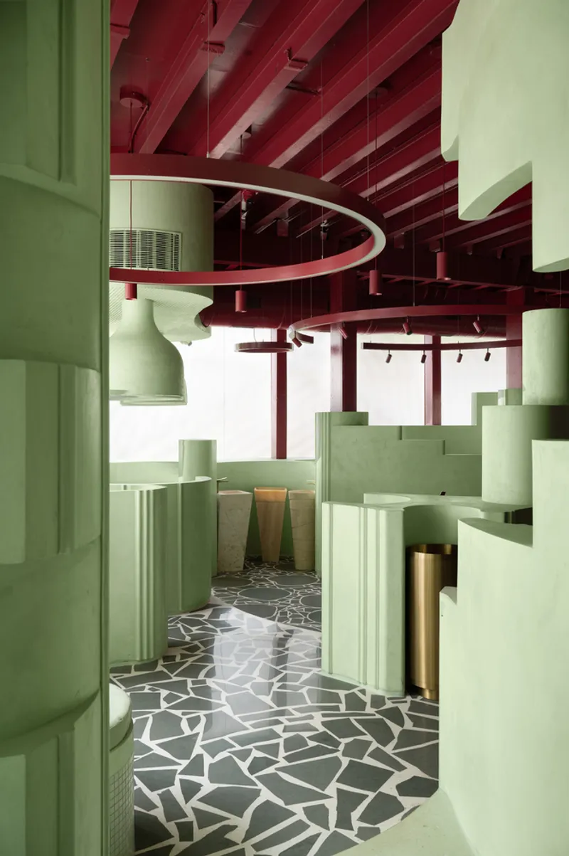 Corridor with partition walls and cylindrical column fragments on terrazzo floor beneath red structural beams