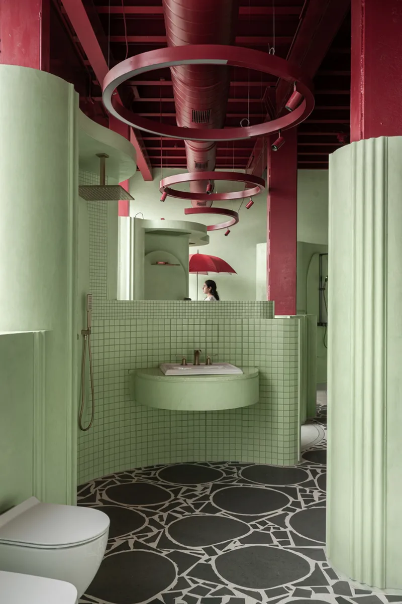 Shower alcove with circular suspended rings overhead and person visible in background mirror