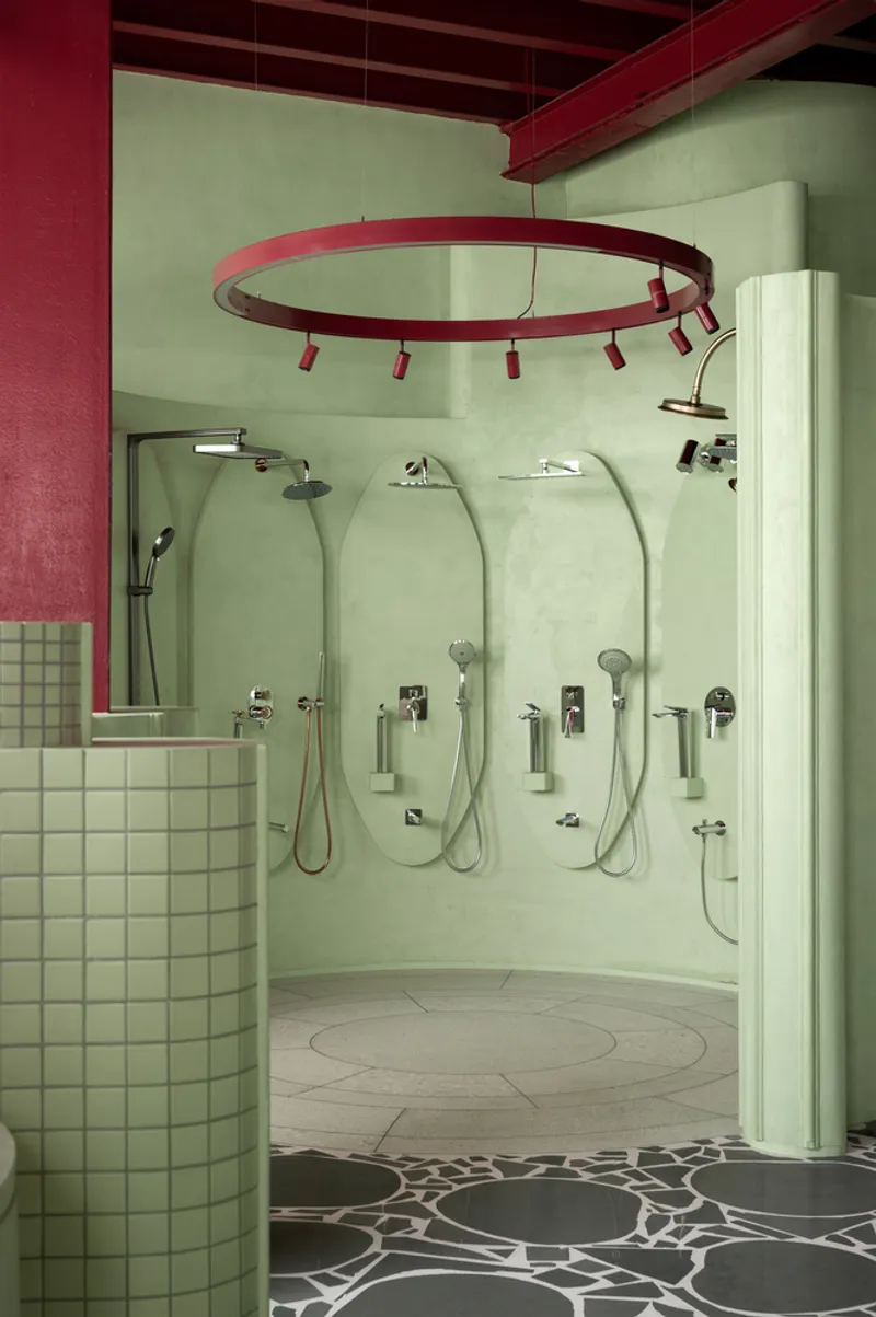 Curved shower wall with multiple rainfall heads and handheld fixtures beneath ring lighting fixture