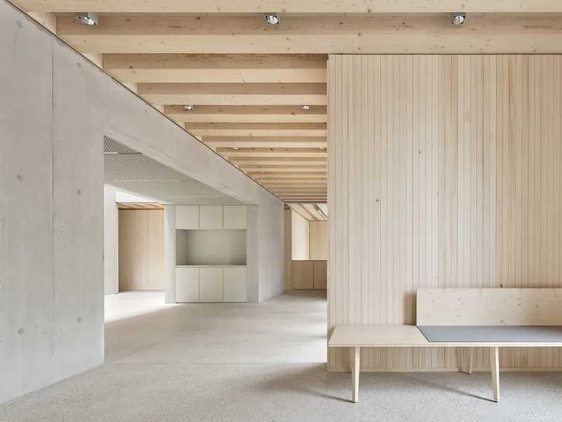 Interior space showing exposed timber joists above terrazzo flooring and a concrete angled partition