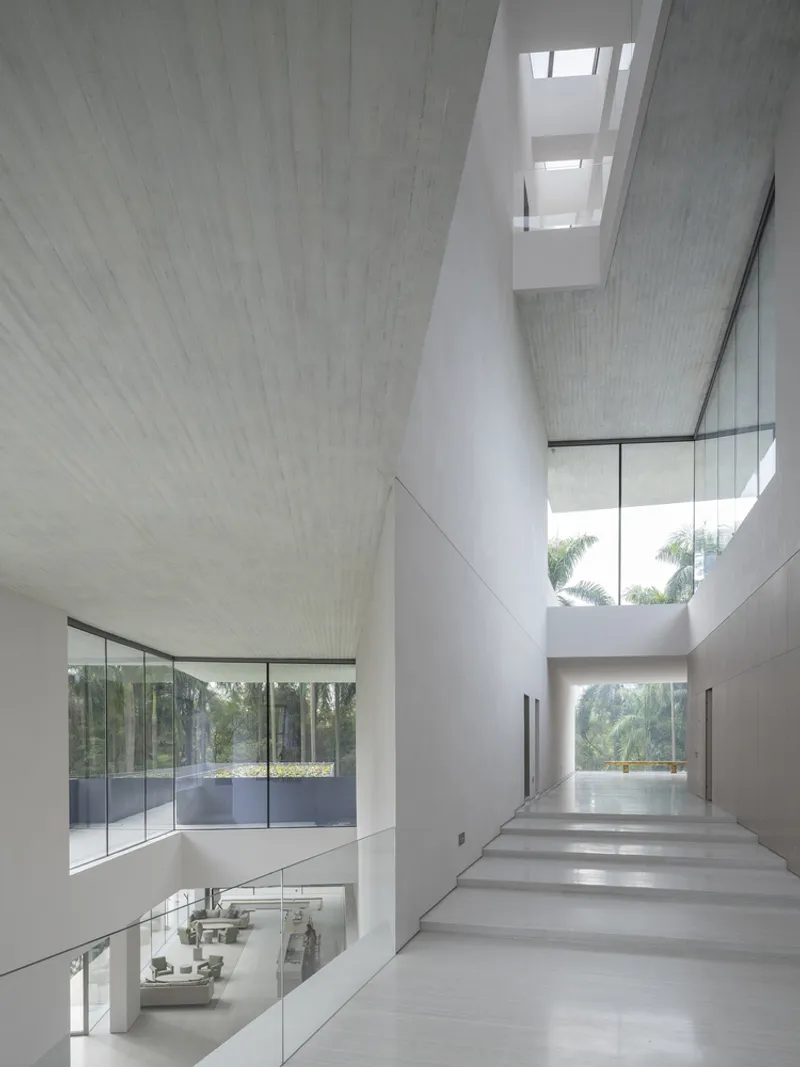 Multistory atrium with cantilevered stairs and textured ceiling panels lit by skylights above