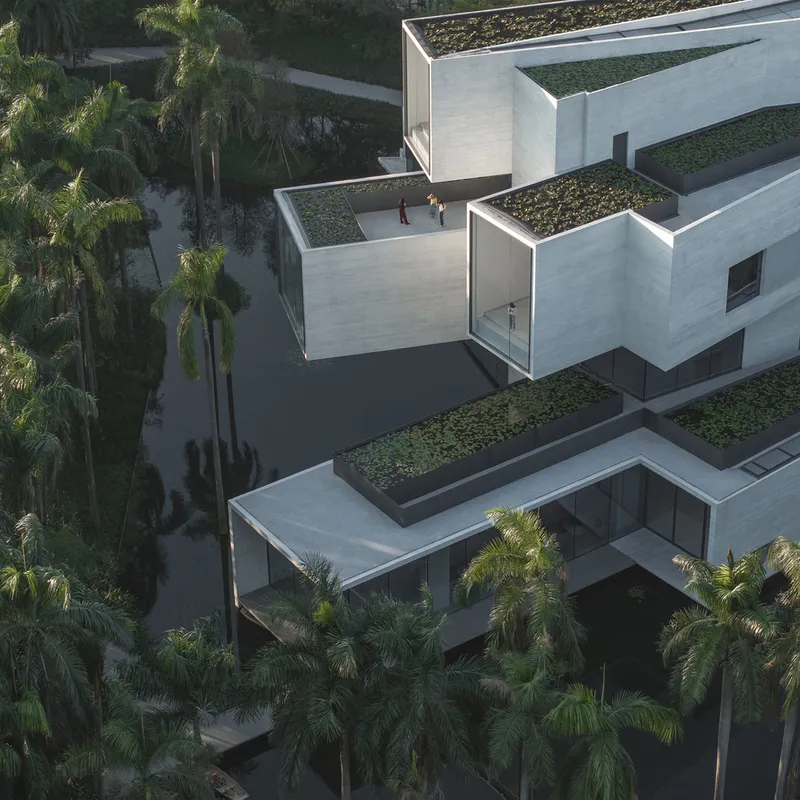 Aerial view of planted green roof terraces with two figures walking between concrete volumes