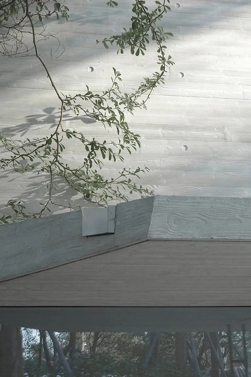 Roof terrace detail with planted tree in metal planter on board-marked concrete paving overlooking treetops