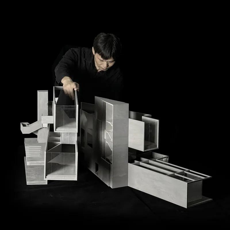 Physical sectional model with translucent and opaque volumes revealing interior spaces as a hand adjusts one piece