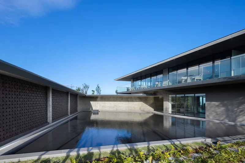 Courtyard with reflecting pool flanked by perforated screen wall and glazed upper level pavilion