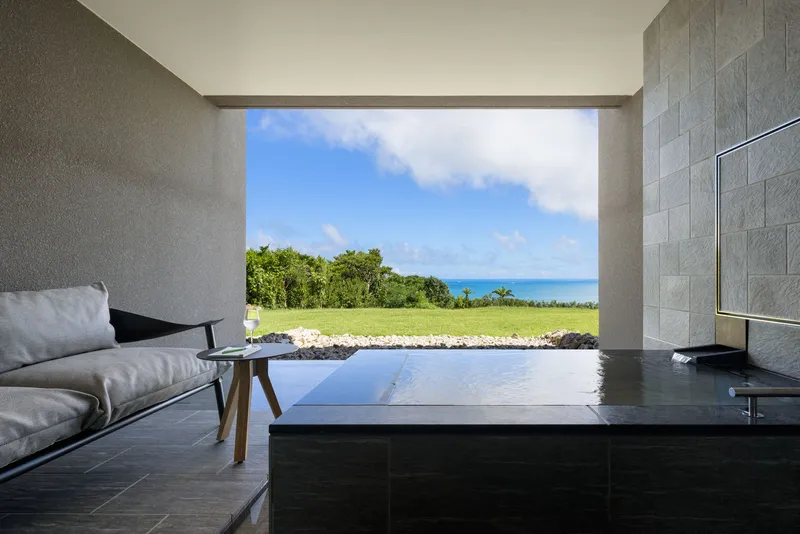 Bathroom with black stone floor and picture window framing lawn and ocean view