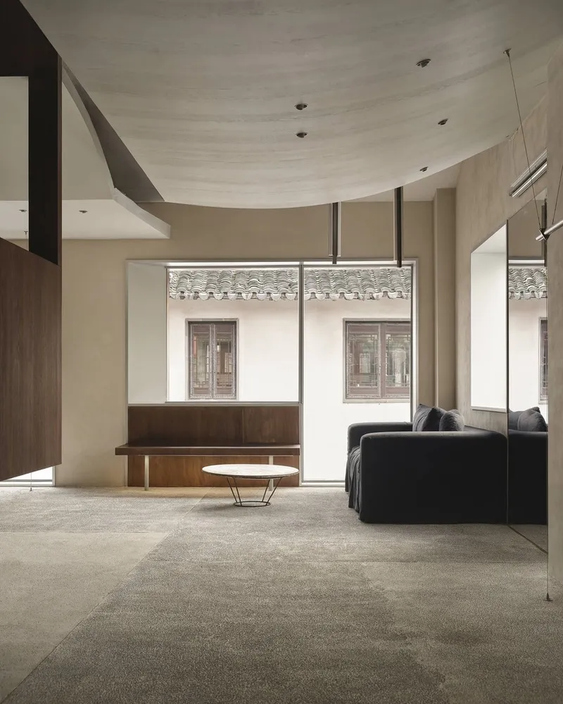Living area with curved plaster ceiling and floor-to-ceiling windows framing a traditional tiled roof courtyard