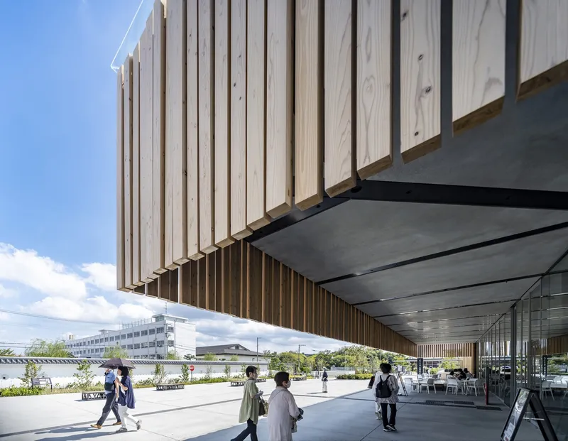 Underside of the timber-clad canopy revealing metal soffit panels and exposed structural supports above the plaza