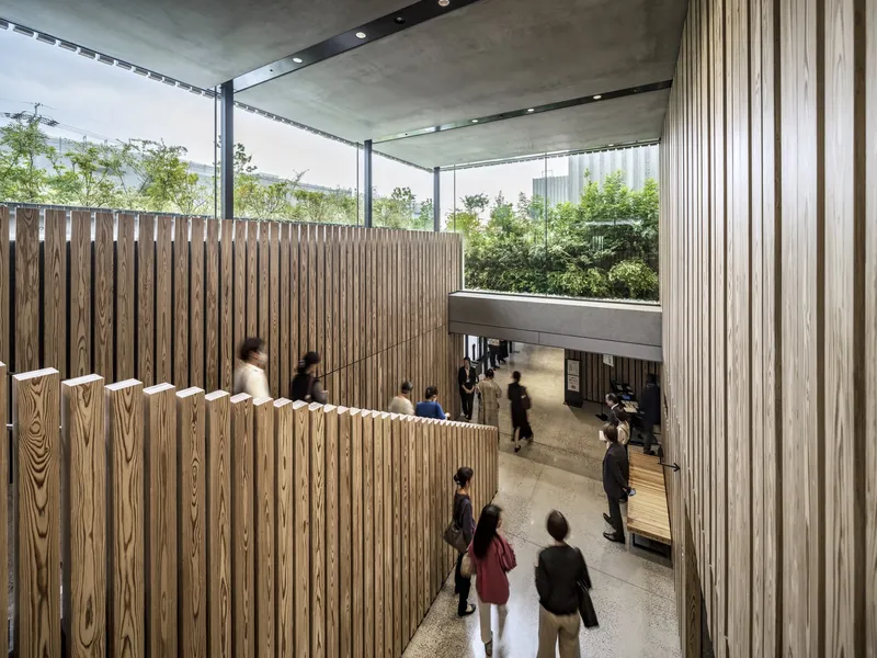 Multi-level interior atrium space with timber-clad mezzanine and glass-roofed upper terrace with greenery