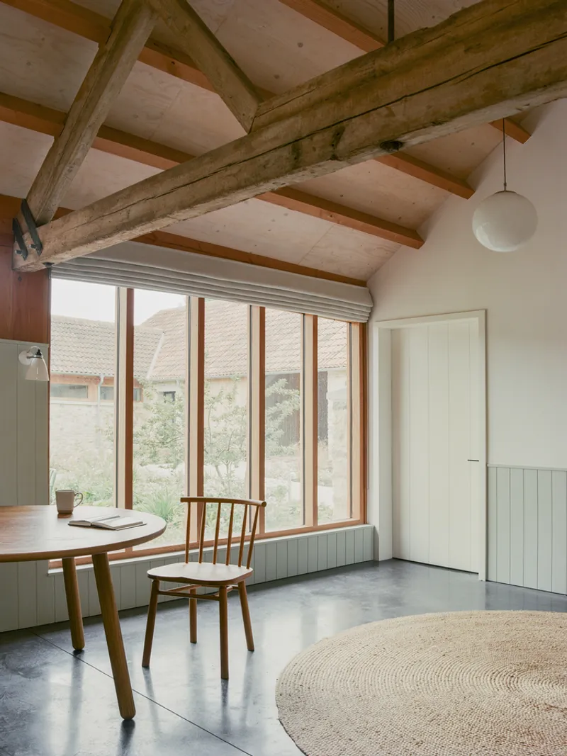 Dining area with vertical timber windows and exposed ceiling beams above polished concrete floor